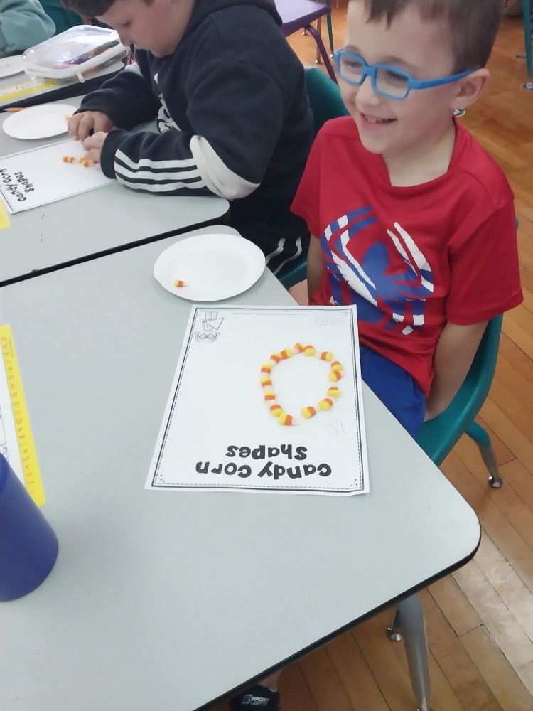First grade student makes shapes using candy corn. 