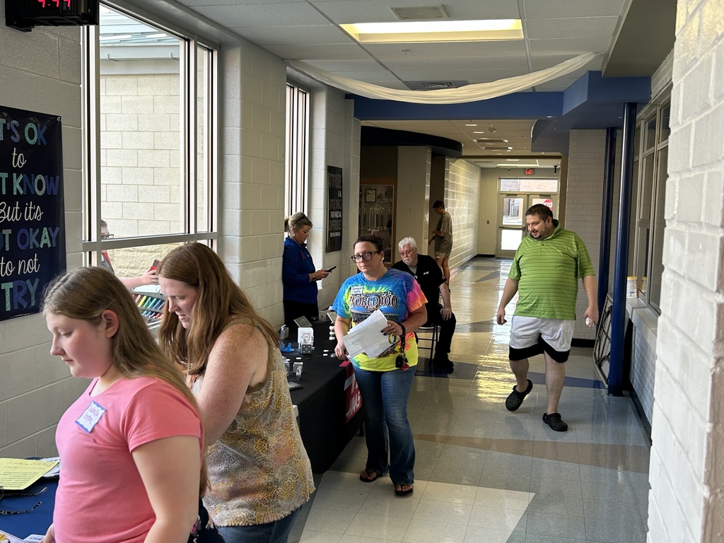 A community partner speaks with a student and family members at an information table during SPARK 360 Family Transition Night
