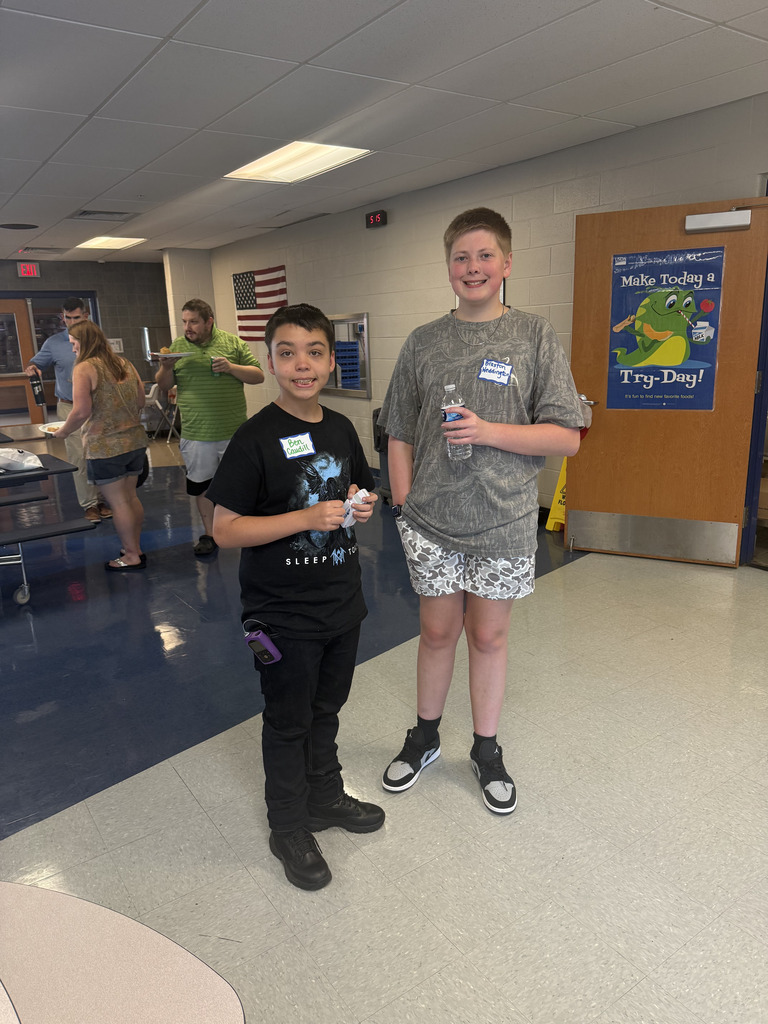 Two students smile for the camera during SPARK 360 Family Transition Night, with other participants visible in the background.