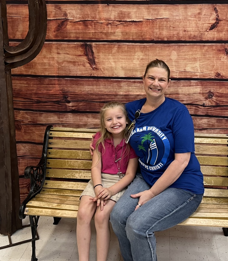 Parent with student at table with red and white checkered table cloth eating breakfast