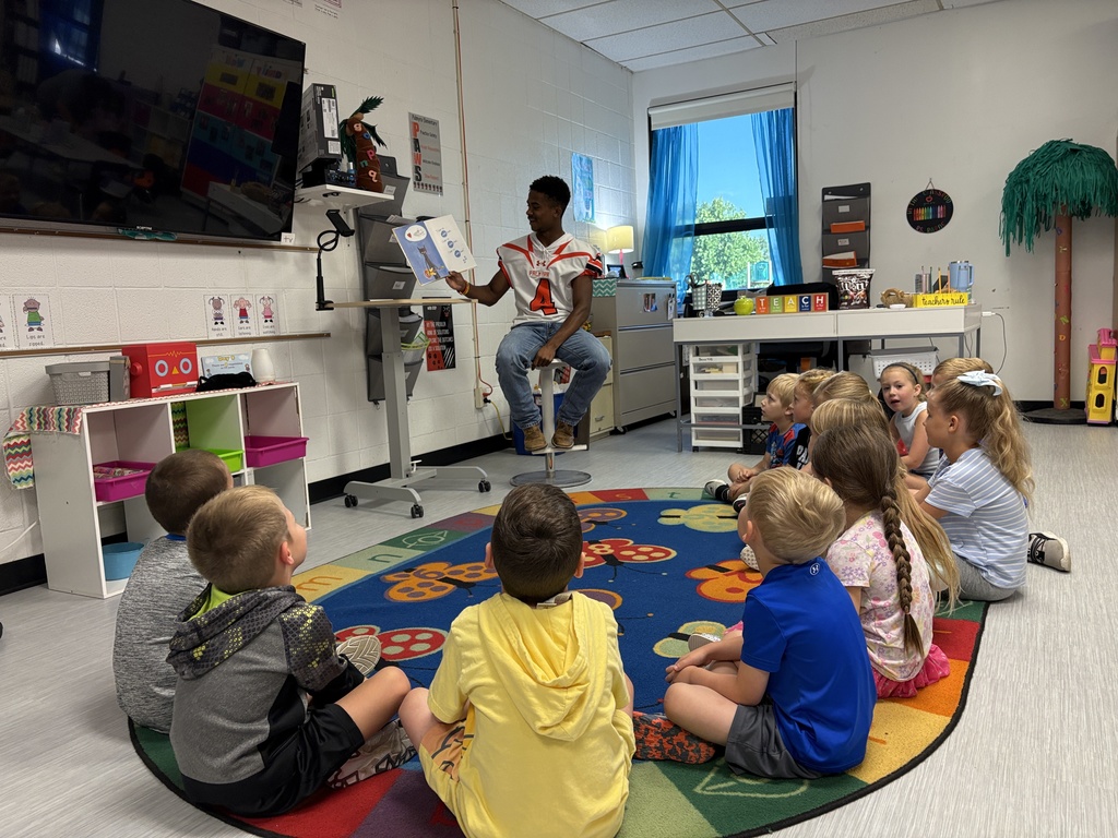Kindergarten listening to football players and coach read books