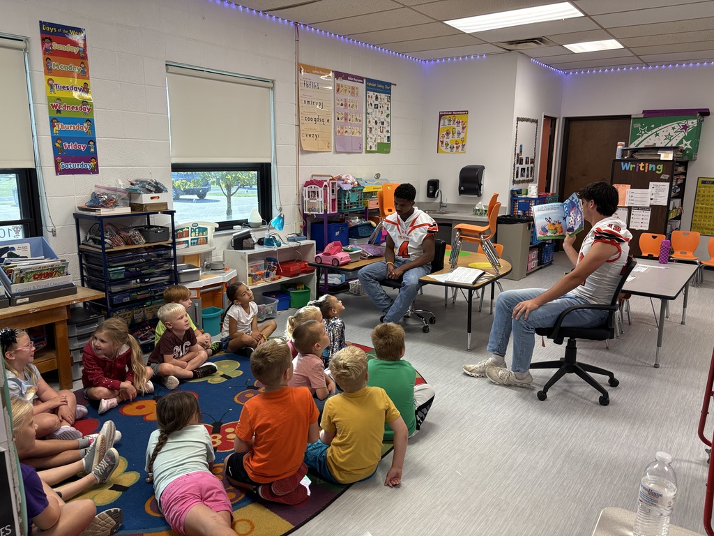 Kindergarten listening to football players and coach read books