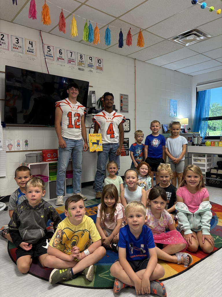 Kindergarten listening to football players and coach read books
