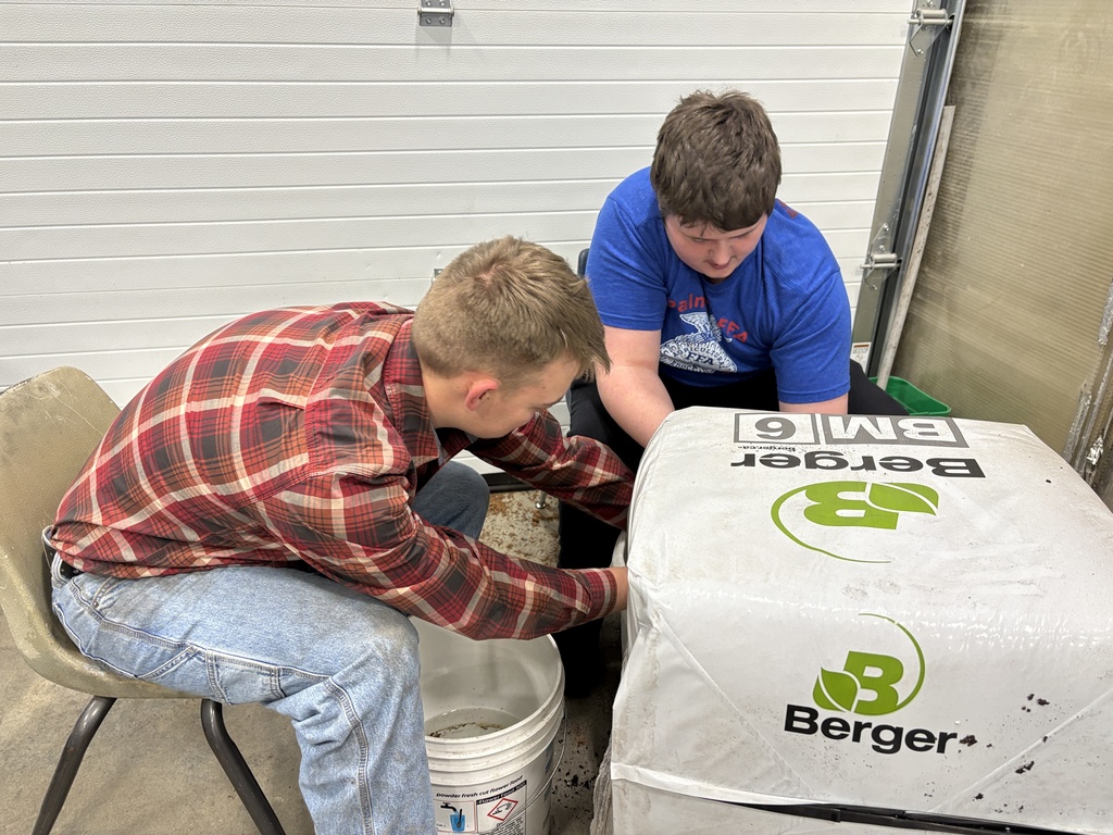 2 students working in the dirt for greenhouse plants