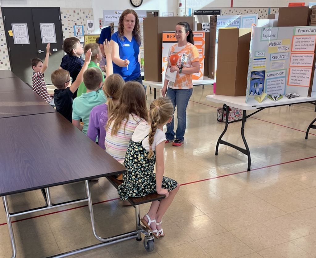 Science fair judge discusses projects with a group of students