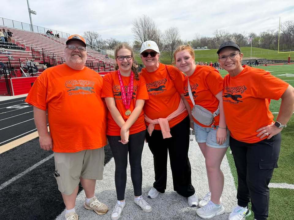 Student with award at Special Olympics with staff and buddies