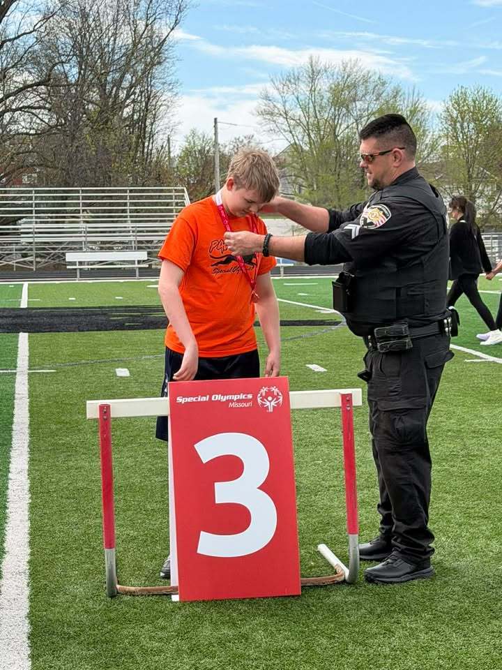 student receiving award at Special Olympics from a police office