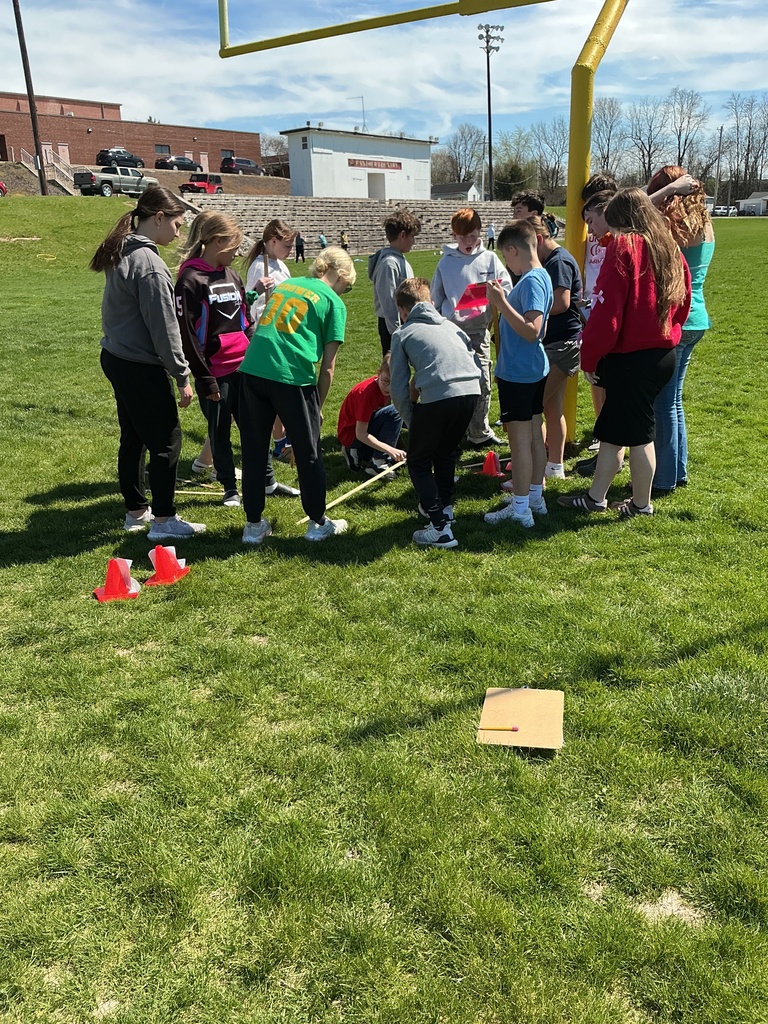 science students studying the scale of the solar system outside on football field