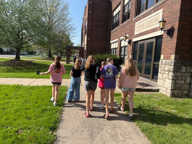 middle school students outside exploring nature looking for spiders