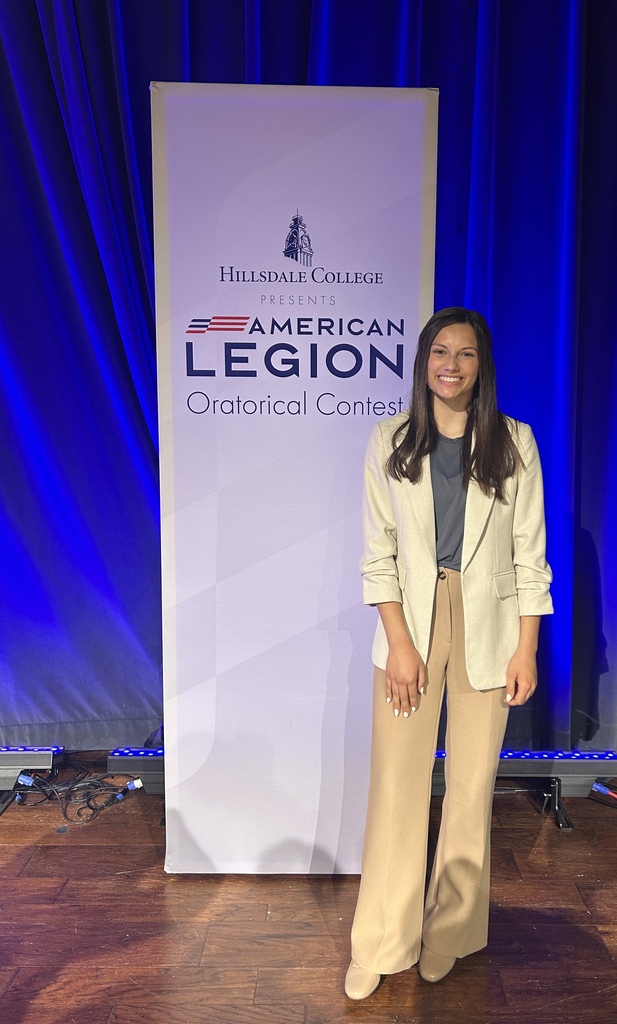 student standing in front of banner, Hillsdale College presents the American Legion Oratorical Contest
