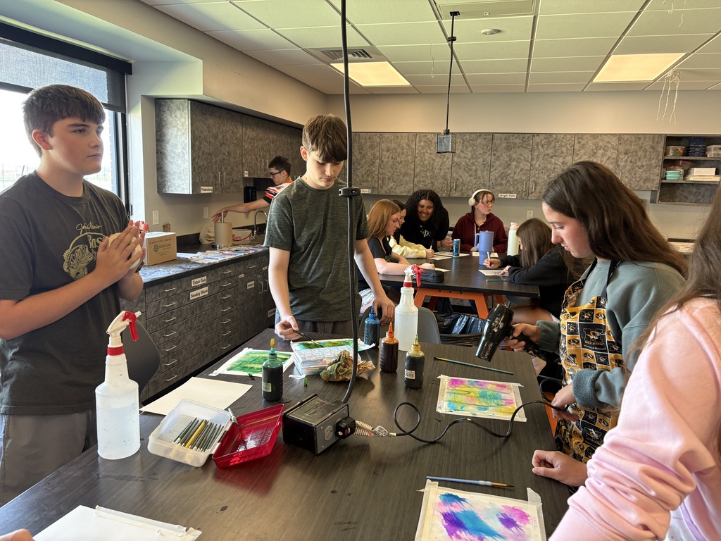 students working with watercolor paint to create colorful artwork