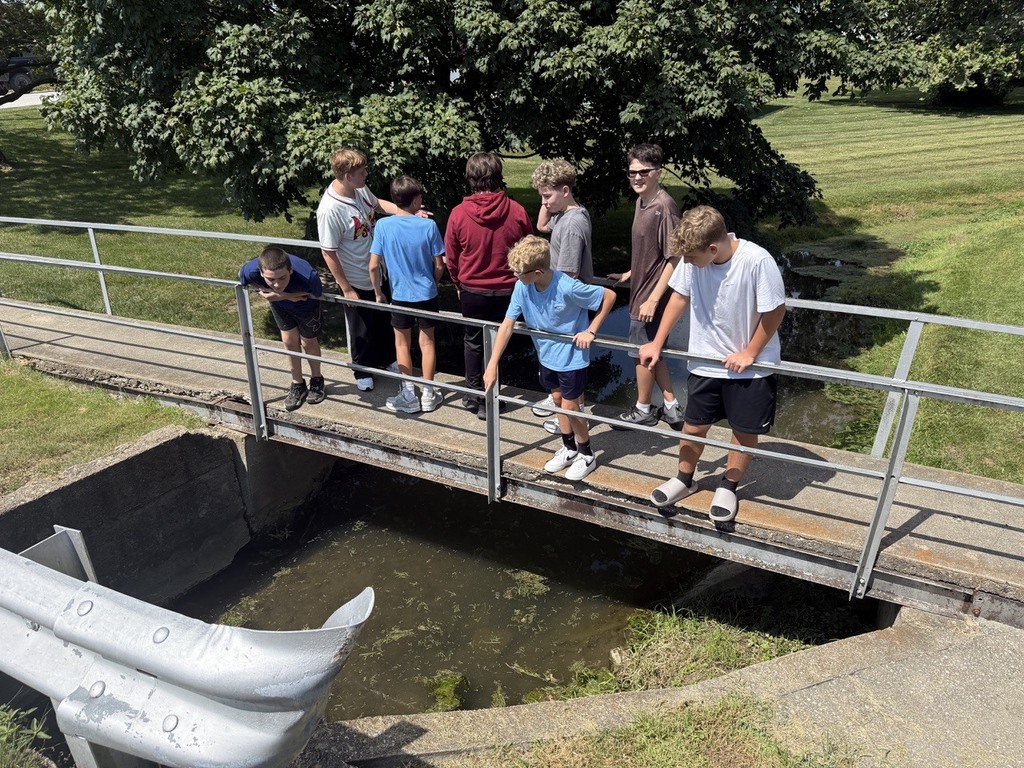 many students on bridge observing habitat in creek near middle school