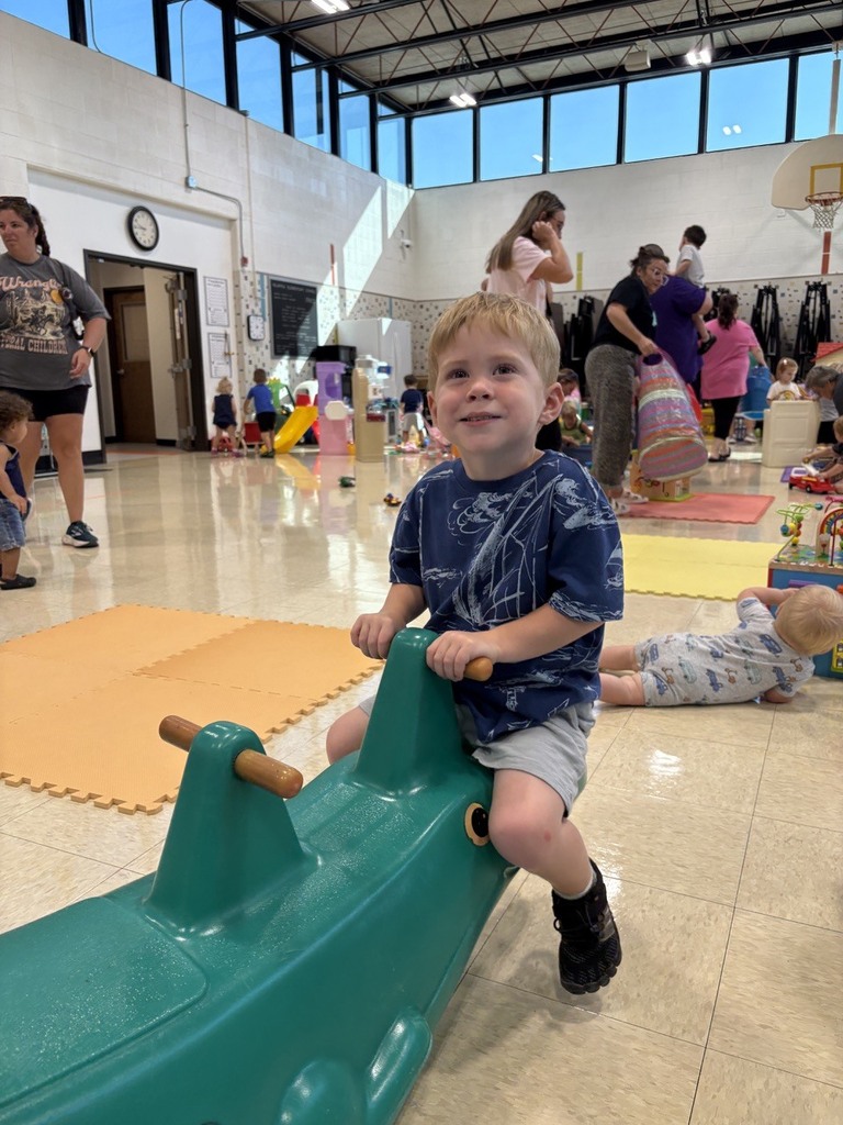 PAT playgroup participant riding on green alligator teeter totter
