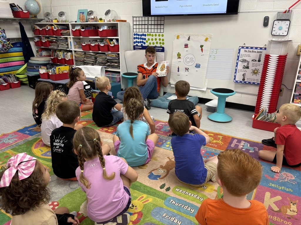 football player reading to kindergarten students