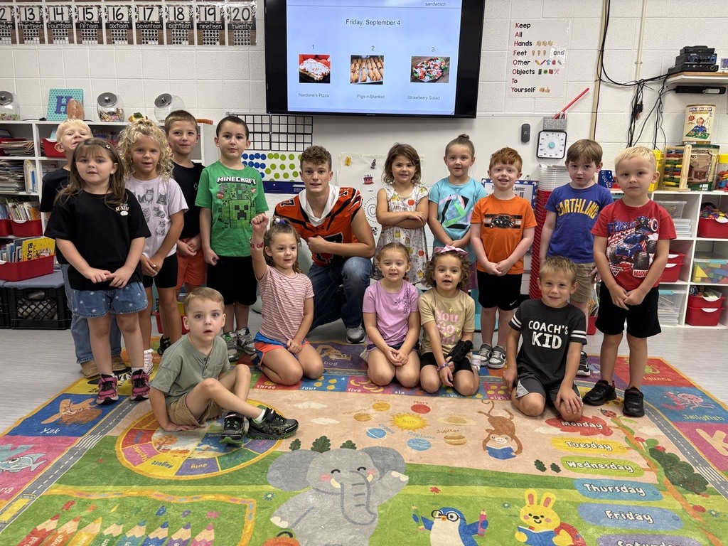football player reading to kindergarten students