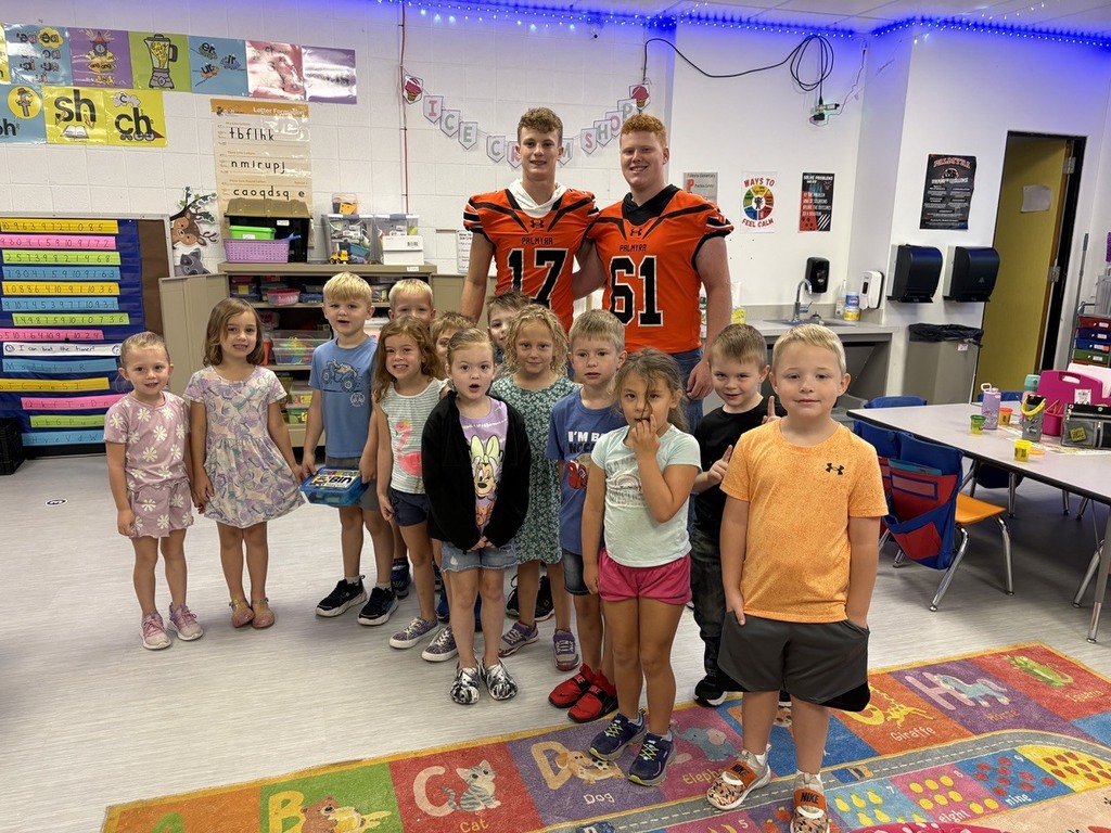 football player reading to kindergarten students