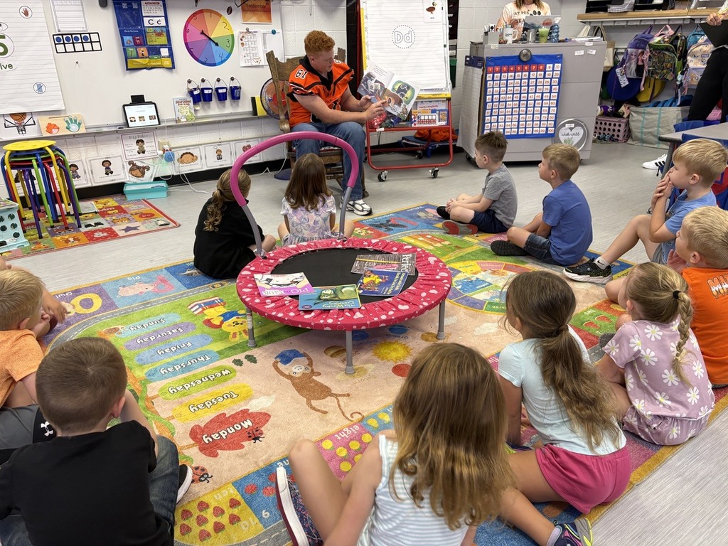 football player reading to kindergarten students