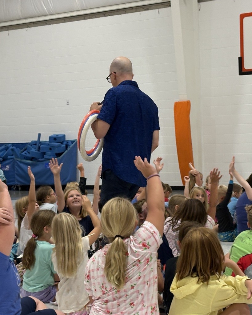 Man with hoops looking for volunteer students during assembly