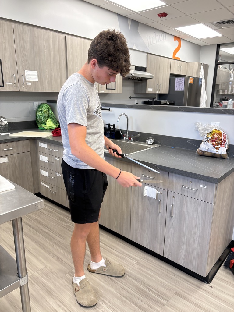 Foods class student practicing knife sharpening