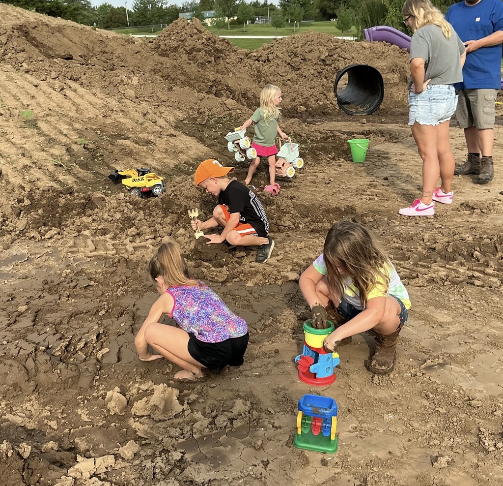 young children playing in dirt with shovels and trucks