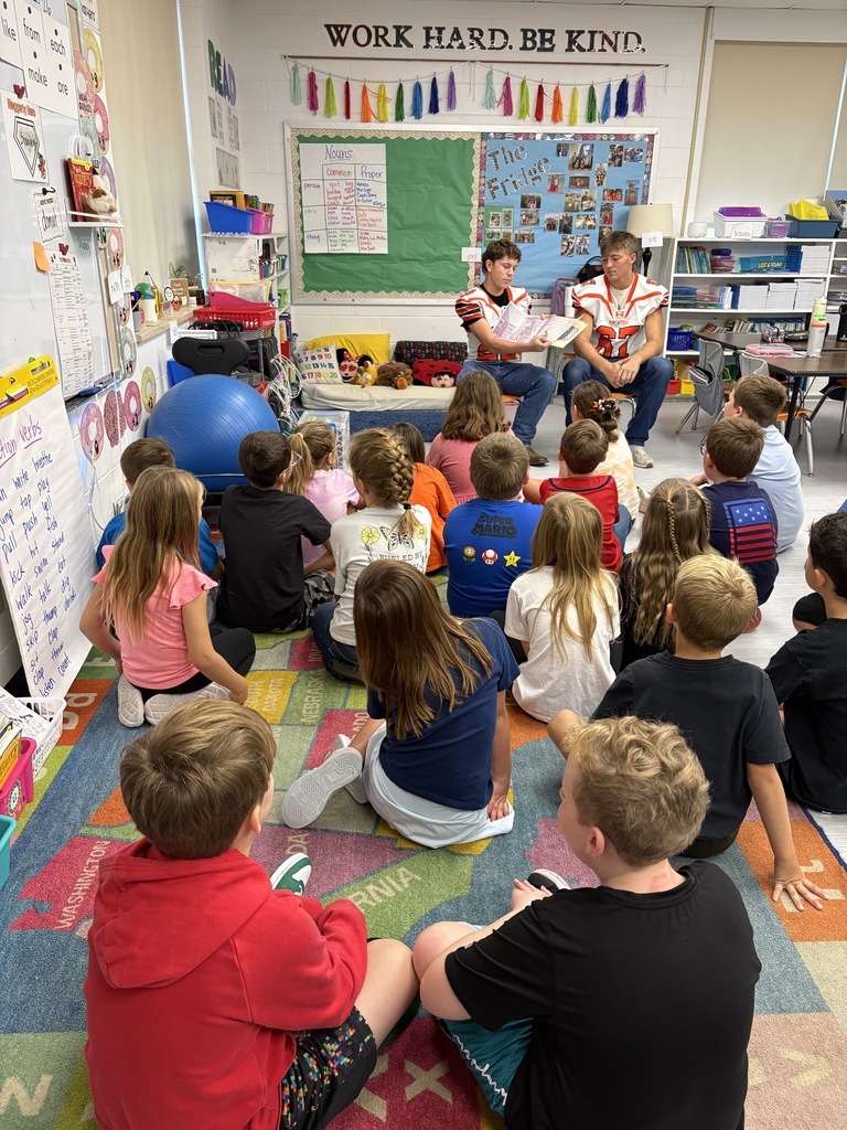 students listening to football players read a book 
