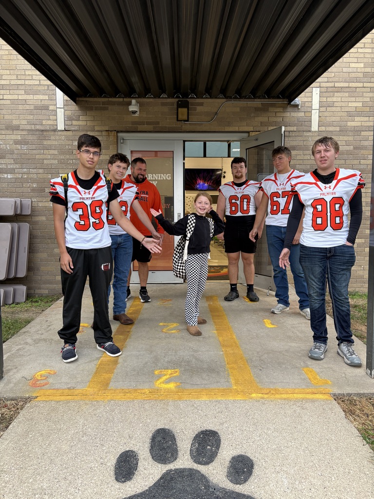 football players greeting students at car rider drop off