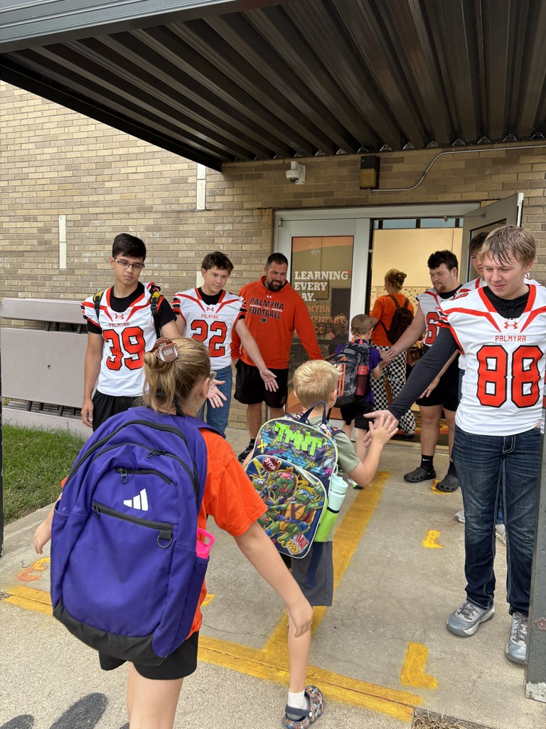 football players greeting students at car rider drop off
