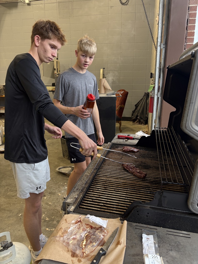 students putting meat on grill to cook