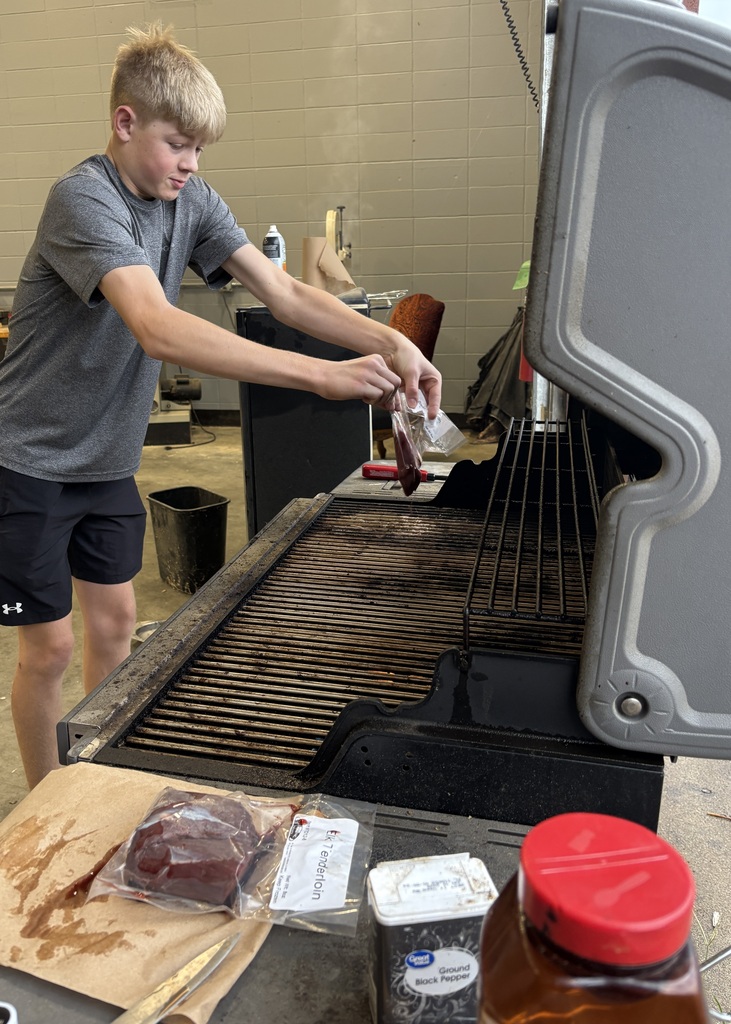student putting meat on grill to cook