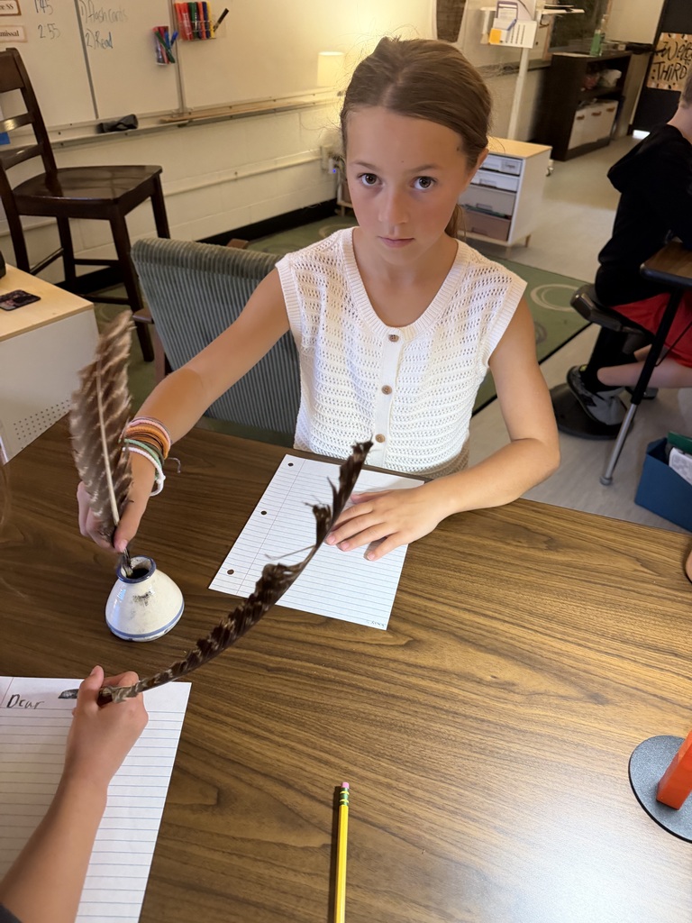 student using quill and ink to write on paper