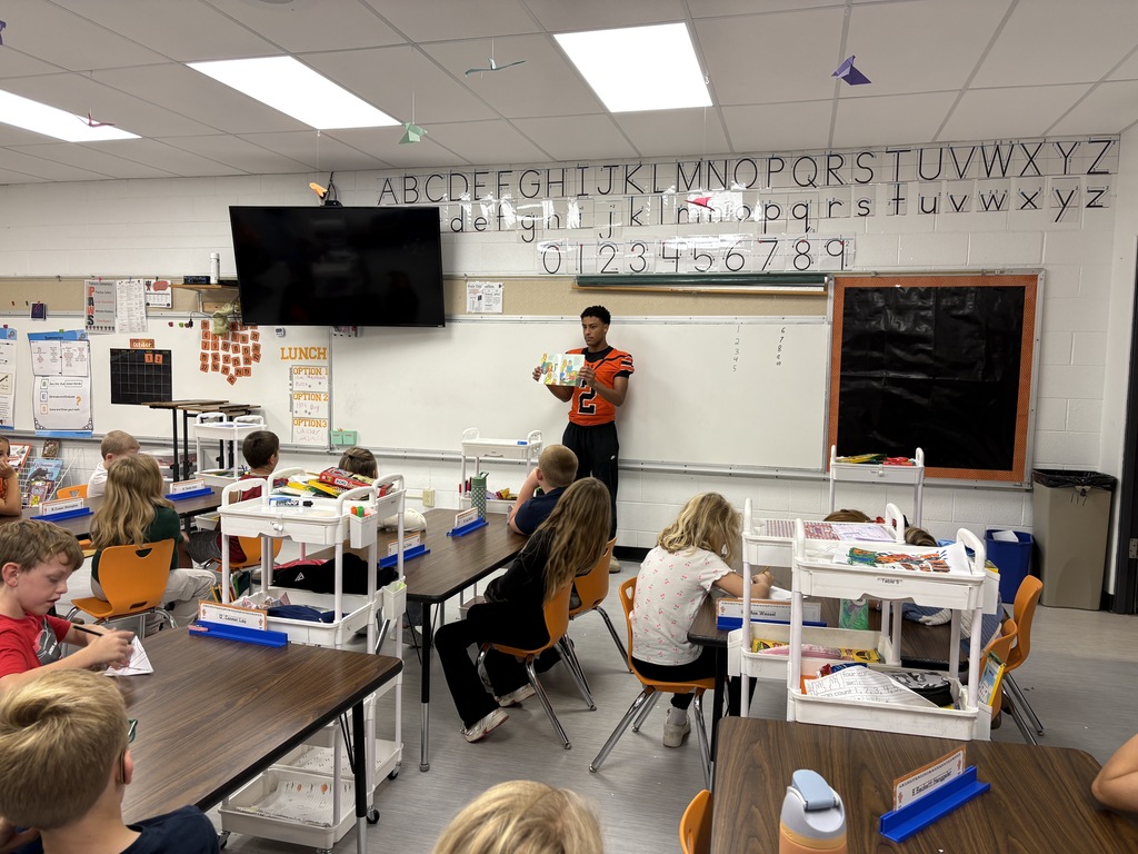 High school football player reading to 2nd grade class