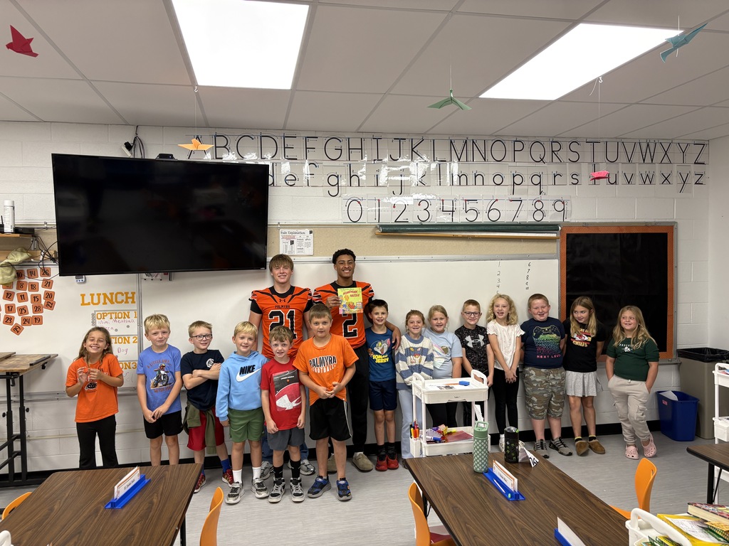 High school football player reading to 2nd grade class