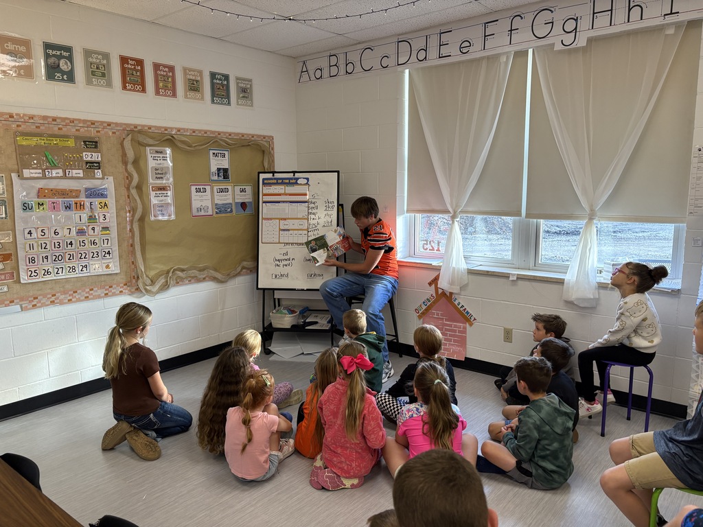 High school football player reading to 2nd grade class