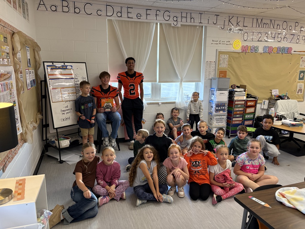 High school football player reading to 2nd grade class