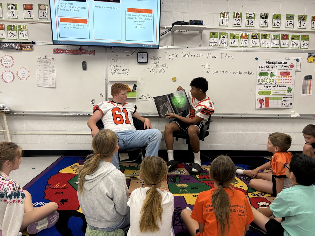 classroom students with 2 football players reading a book