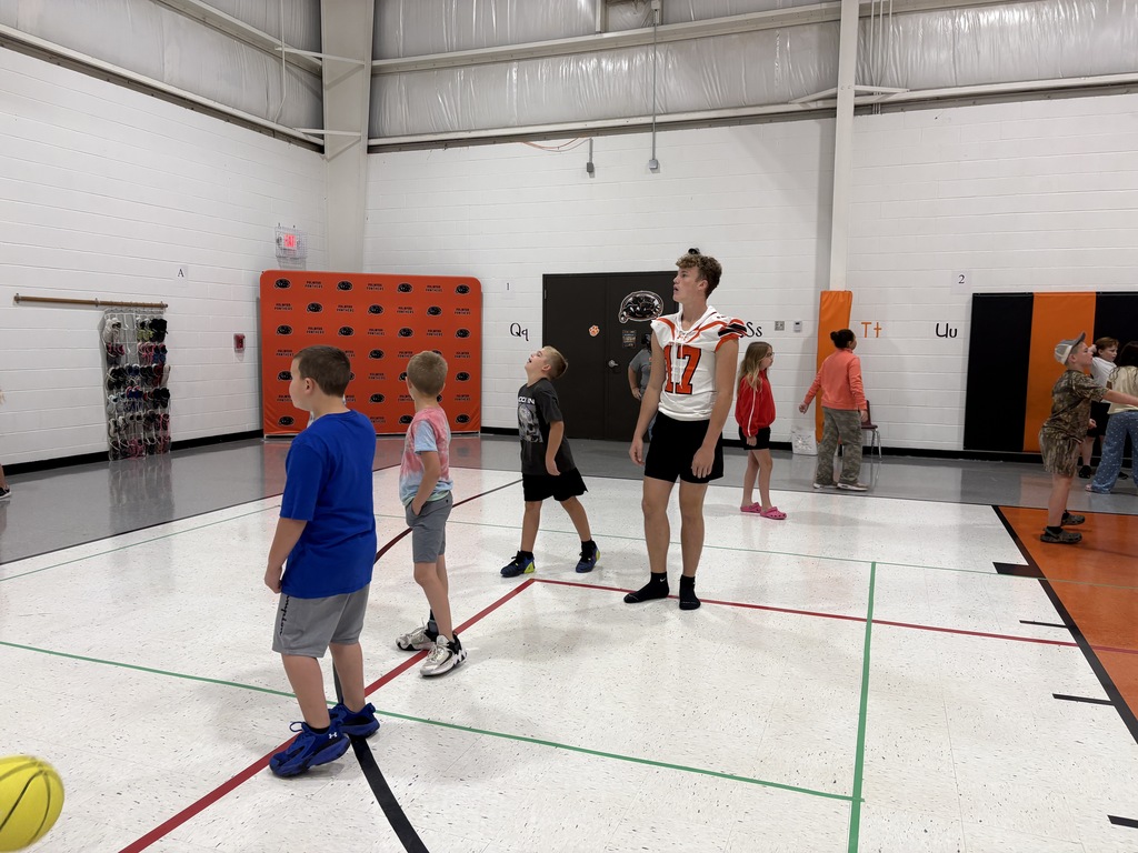 football player playing basketball with elementary students