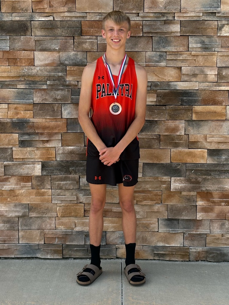 Runner wearing medal standing against stone wall