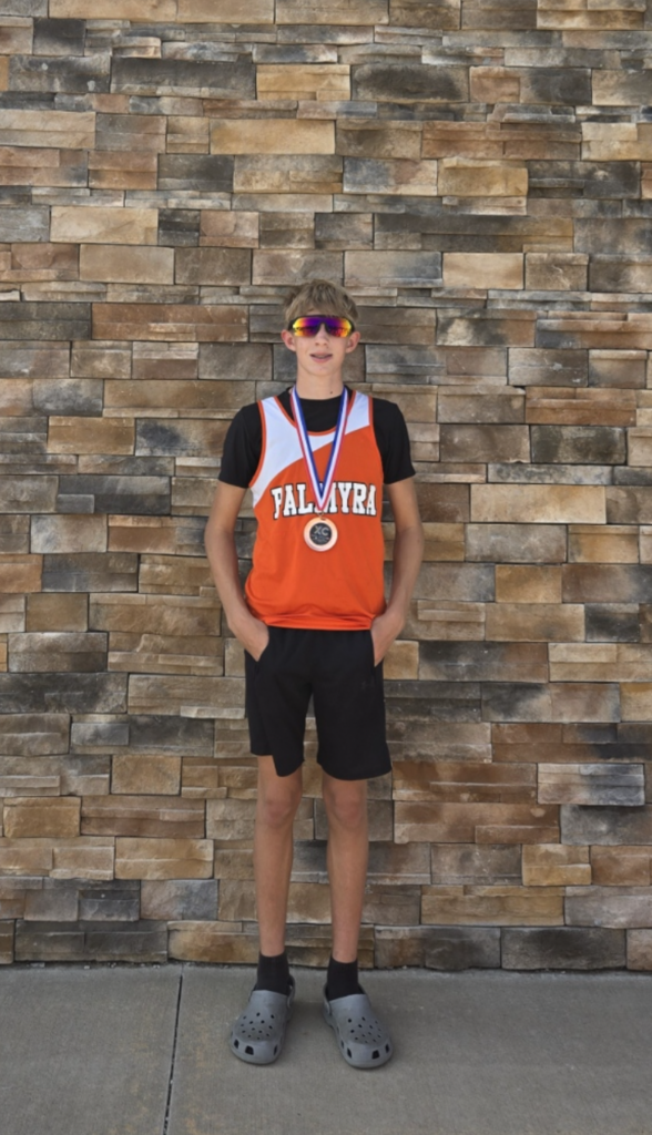 Runner wearing medal standing against stone wall