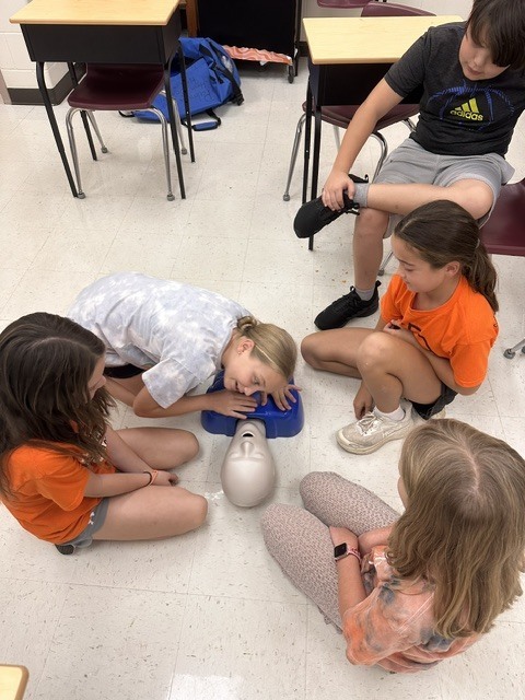 5th grade Health students practicing CPR and the Heimlich maneuver on dummies