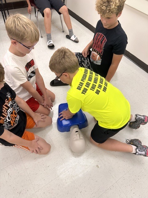 5th grade Health students practicing CPR and the Heimlich maneuver on dummies