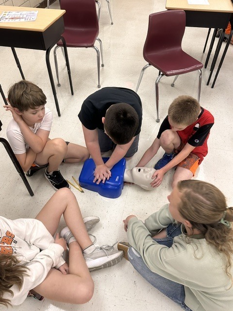 5th grade Health students practicing CPR and the Heimlich maneuver on dummies
