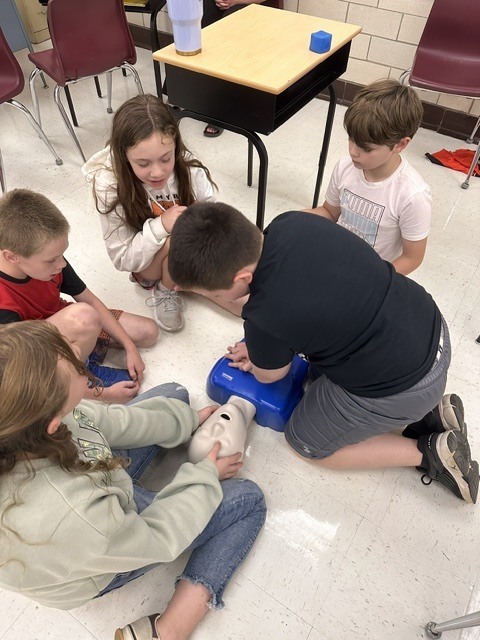 5th grade Health students practicing CPR and the Heimlich maneuver on dummies