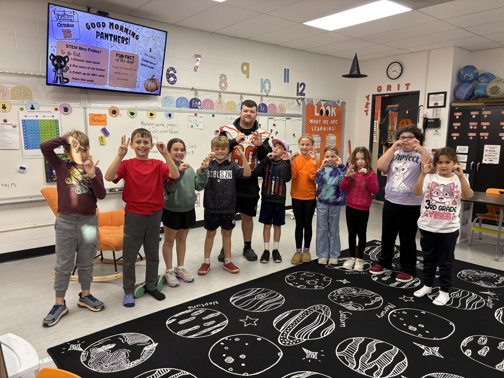 football player reading to 3rd grade students