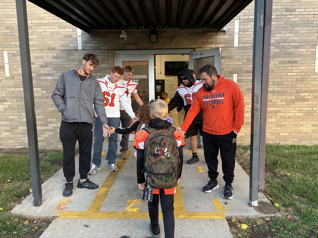 football players greeting students at car rider drop off