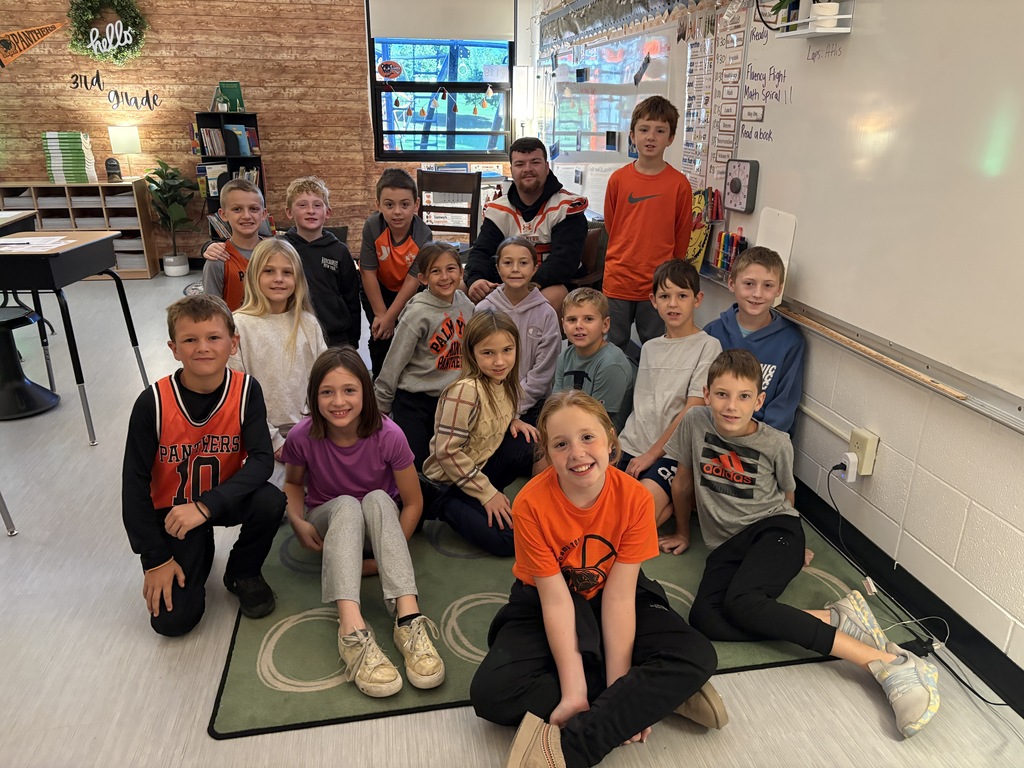 football player reading to 3rd grade students