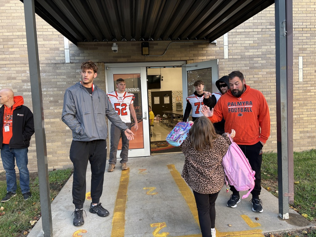 football players greeting students at car rider drop off