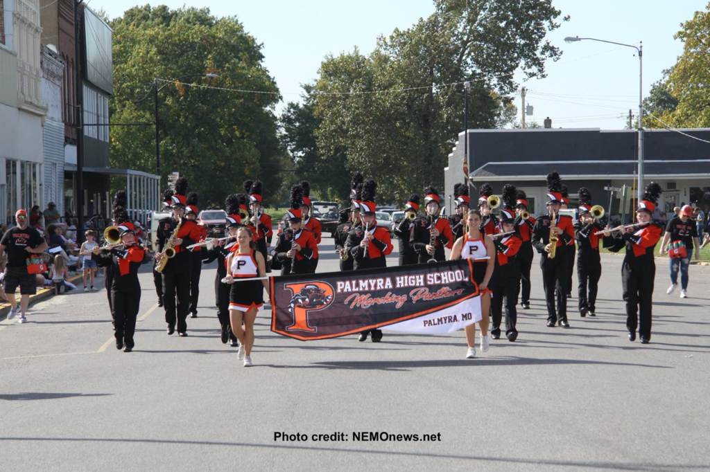 band marching in parade with Palmyra High School banner