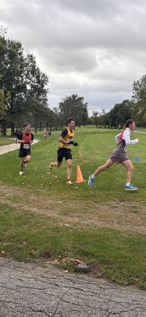 3 XC runners going around orange cone