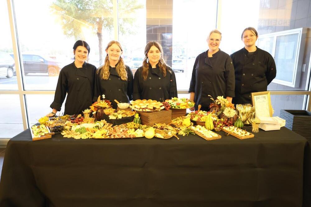 Culinary Arts students and teacher standing in from of table filled with food that they catered for the Hall of Fame Reception