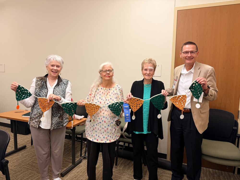 ladies and superintendent holding green and gold crocheted banners